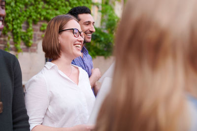 Smiling young woman with friends singing in choir outside language school