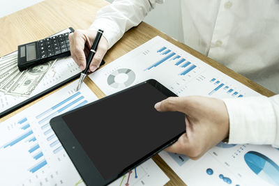 Midsection of businessman writing in graph while using digital tablet on table