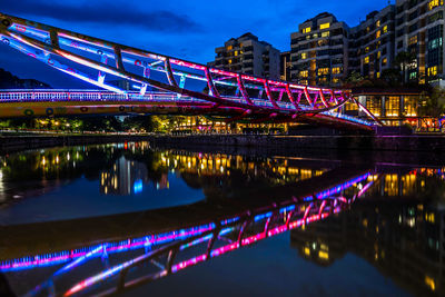 Illuminated bridge over river in city at night