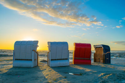 Hooded beach chairs at beach during sunset