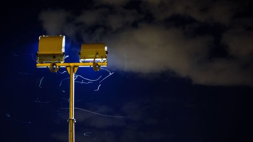 Close-up of yellow pole against sky at night