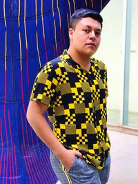 Portrait of young man standing against curtain at home