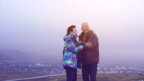 Rear view of couple standing on mountain against sky