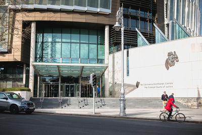 People riding bicycle on road against buildings