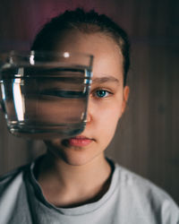 Close-up portrait of woman by glass of water