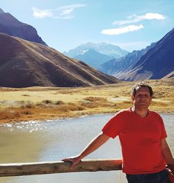 Portrait of man standing with lake and mountain in backgrounds against sky