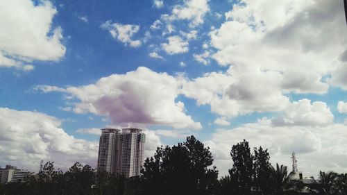 Low angle view of trees against cloudy sky