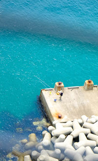 Aerial view of person fishing by blue river on sunny day