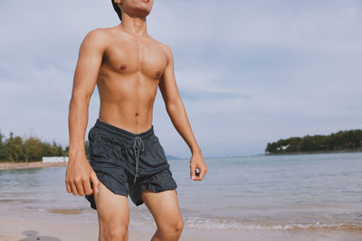 Shirtless man standing at beach