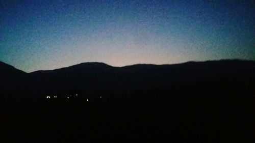 Scenic view of silhouette mountains against clear sky at night