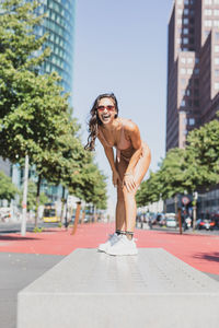 Young woman wearing bikini while laughing in city during sunny day