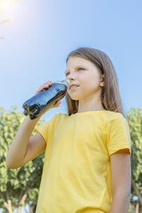A young girl drinks soda from a plastic bottle. vertical shot.