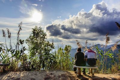 Rear view of couple sitting on land against sky