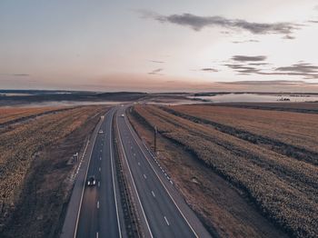 Aerial view of road on land against sky at sunset