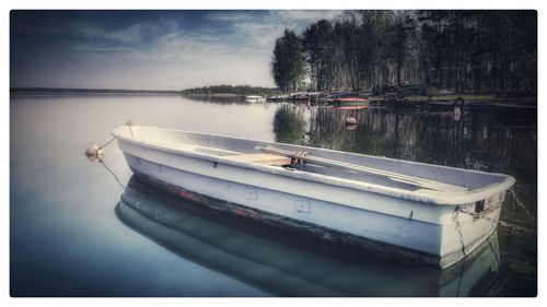 Boat moored in lake against sky