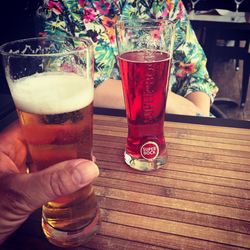 Midsection of woman holding beer glass on table