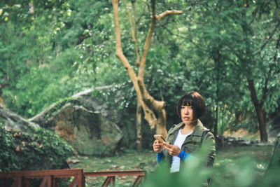 Full length of woman looking at camera in forest