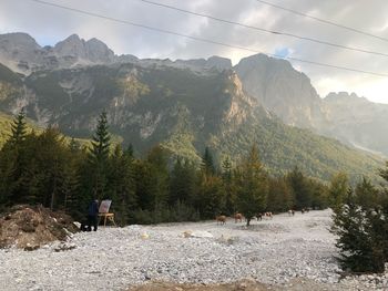 Rear view of people walking on street amidst mountains against sky