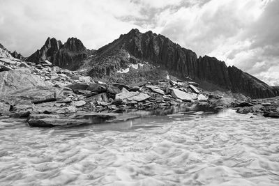 Scenic view of sea by mountain against sky