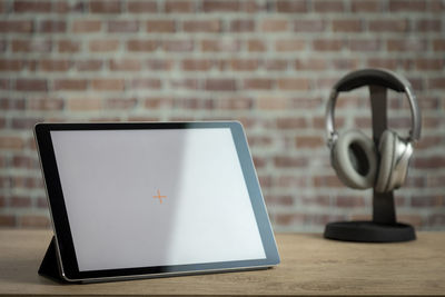 Close-up of laptop on table against wall