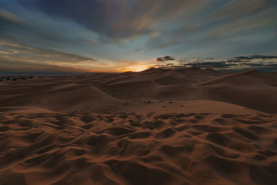 Scenic view of sand dunes against sky during sunset