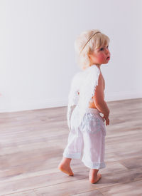 Cute girl looking away while standing on wooden floor