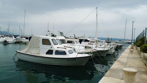 Sailboats moored at harbor against sky