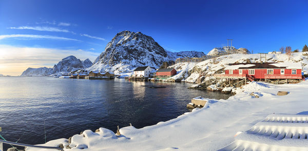 Houses by snowcapped mountains against blue sky