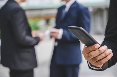 Midsection of man holding mobile phone