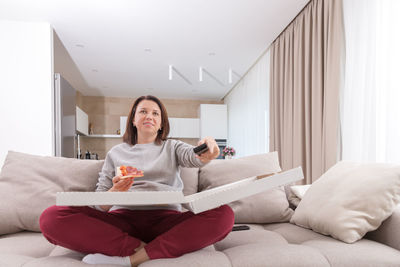 Young woman using laptop while lying on bed at home