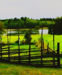 Scenic view of field by lake against sky