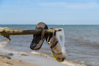 Close-up of rusty metal on beach against sky