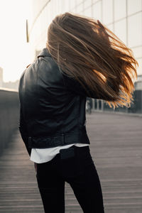 Rear view of woman with umbrella standing on street