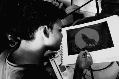 High angle view of young man painting in book at home