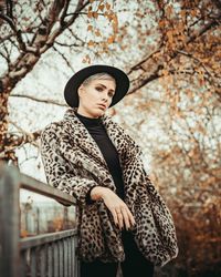 Woman looking away while standing against tree