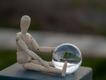 Close-up of human figurine with crystal ball on table