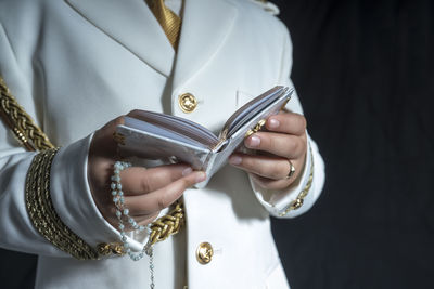 Midsection of man holding bible against black background