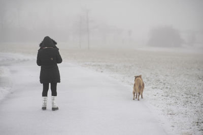Rear view of woman with dog on snow