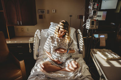 Woman sitting on bed at home