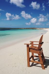 Chairs on beach against cloudy sky