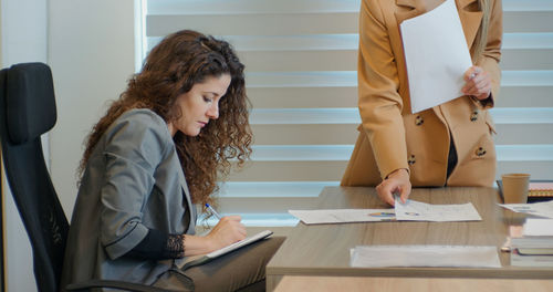 Woman receiving work during a meeting with boss and collegue. 