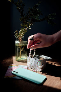 Cropped hand of woman holding gift box on table