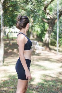 Side view of teenage girl exercising against trees in park