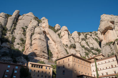 Low angle view of rocks on mountain against clear blue sky