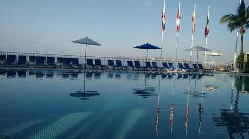 Boats in swimming pool by lake against sky