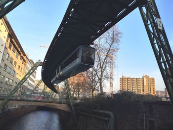 Low angle view of bridge over river amidst buildings in city