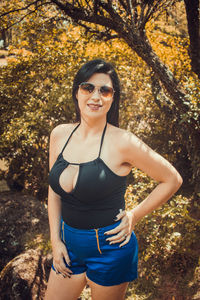 Portrait of woman in sunglasses while standing against plants