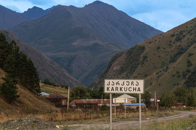 Road sign by mountains against sky