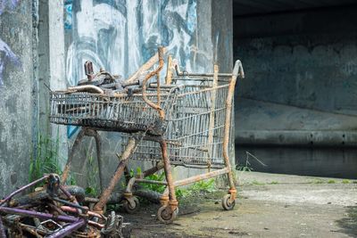 Abandoned shopping cart on street by wall