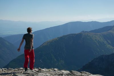 Rear view of man standing on mountain against sky